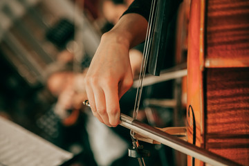 Symphony orchestra on stage, hands playing cello