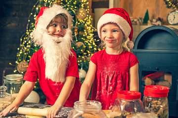 Funny Santa chef. Christmas cookies. Merry Christmas. Little boy and cute little girl with santa hat preparing cookies in the kitchen at home.