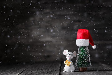 Mouse, Santa Claus Hat and spruce tree on wooden rustic background with snow. New Year celebration