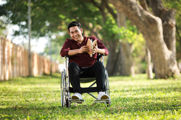 Fototapeta na wymiar Asian Young Man sitting on the wheelchair in the park hospital