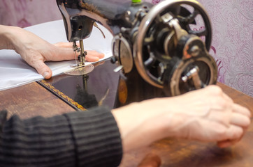 Woman working on an old sewing machine. Hands close-up