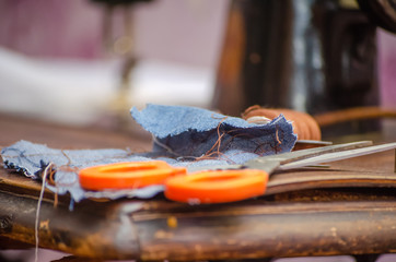 piece of blue cloth, a spool of sewing machine, scissors on a wooden table close-up
