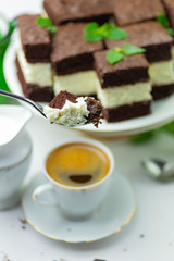 Close-up of chocolate cake on a fork, in the background more chocolade cakes and a cup with coffee