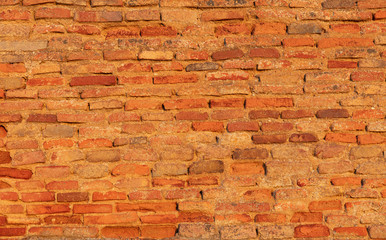 A very old wall made of brick reddish stones on a church. The old clinker wall looks very antique. Interesting background with a retro look.