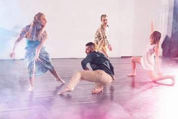 Group of modern male and female street dancers performing different moves in the studio. Effective performance. Beautiful dance.