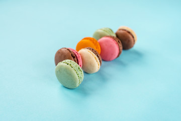 Range of multicolored french macaroons on blue background, close up, copy space.