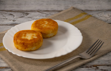 cheesecakes on a white plate with a fork on a grey linen napkin on a table