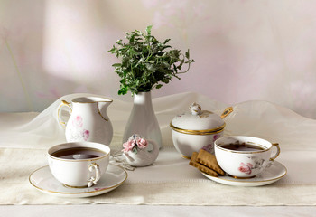 Cups with tea, cookies and a bouquet on the table close-up.
