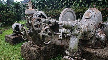 A statue of a tea leaf processing machine monument in a park on a mountain