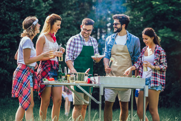 Young friends having fun grilling meat enjoying barbecue party.