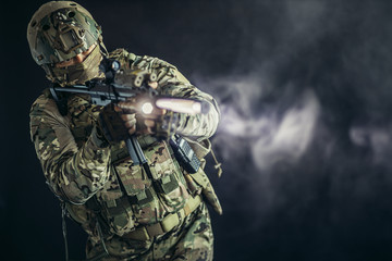 young man from military forces in green military wear try to shoot on rifle gun through smoke fogger