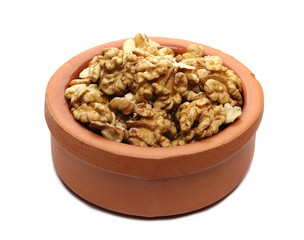 Walnut kernels in clay pot isolated on white background