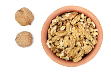 Walnut kernels in clay pot isolated on white background, top view