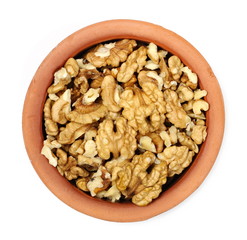 Walnut kernels in clay pot isolated on white background, top view