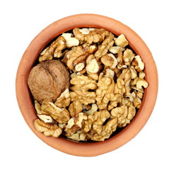 Walnut kernels in clay pot isolated on white background, top view