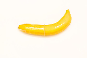 Transparent condom on banana isolated on white background. Conceptual photography of contraception, safe sex and sex education. Blank space for text, top view