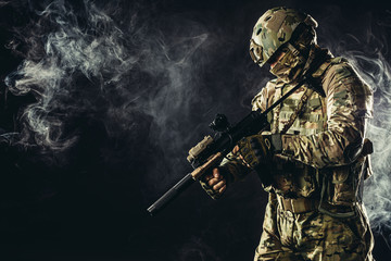 young man from military forces in green military wear try to shoot on rifle gun through smoke fogger