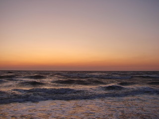 Landscape of vast sea horizon against a background of blue sky decorated with rainbow shades of summer dawn.