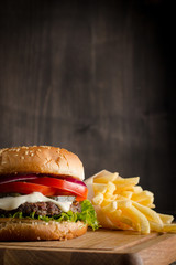 Home made hamburger with beef, onion, tomato, lettuce and cheese. Fresh burger close up on wooden...