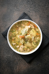 Fresh homemade fish soup with vegetables in bowl on black background, top view with copy space.
