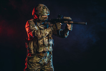safety and protection concept. young man work as military man protecting country, wearing military forces clothes and holding gun in smoky UV space