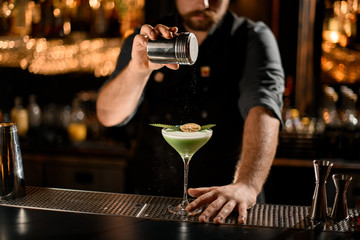 Bartender sprinkles cocktail with eucalyptus and slice of lemon