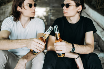 Two Stylish Twins Brothers Having Fun Drinking Beer on the Stairs