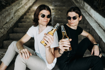 Two Stylish Twins Brothers Having Fun Drinking Beer on the Stairs