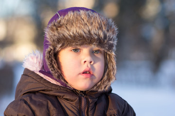 Portrait of the caucasian child of three age looking aside wearing winter cloth hat