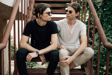 Obraz premium Two Stylish Twins Brothers Sitting on the Stairs