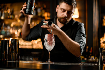 Bartender pours vodka from jigger to glass