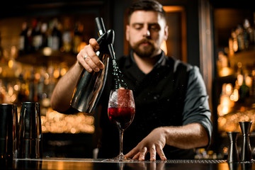 Bartender preparing alcohol cocktail with a pulverizer