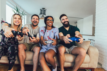 Happy multiethnic friends playing video game and having fun at home.