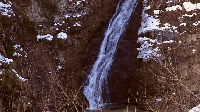 Wasserfall in einer tief eingeschnittenen Schlucht mit Schnee auf den Felsen