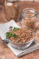 Cooked buckwheat in a glass, transparent bowl, parsley leaf, linen napkin, jars for storing cereals