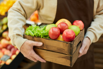 Close up of unrecognizable senior man holding box of apples while selling fruits and vegetables at...