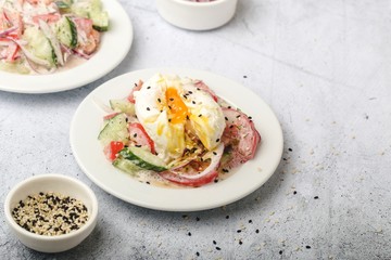 Poached egg on chopped and mixed vegetables with sour cream, scattered sesame seeds, white dishes