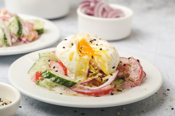 Poached egg on chopped and mixed vegetables with sour cream, scattered sesame seeds,