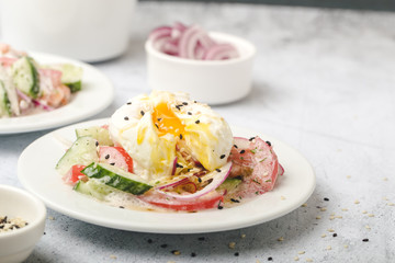 Poached egg on chopped and mixed vegetables with sour cream, scattered sesame seeds