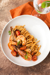Mediterranean cuisine, pasta with king prawns, brown stone background.