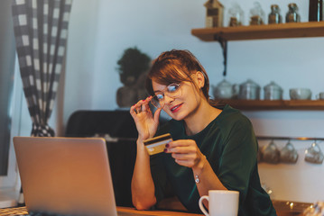 Housewife doing online bill payments and making preparations in the kitchen, Woman with laptop and credit card buying online christmas and new year gifts