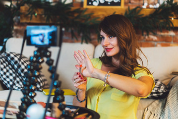 Young woman showing a new lipstick on camera and recording her video. Woman making a video for her beauty blog on cosmetics