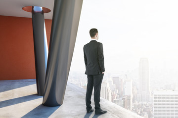 Businessman standing in concrete interior
