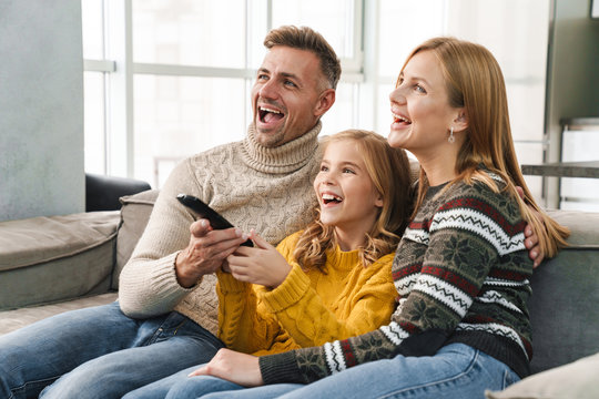 Image of caucasian happy family watching television on sofa at home