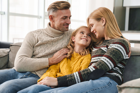 Image of caucasian happy family sitting on sofa together at home