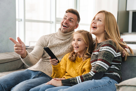 Image of caucasian happy family watching television on sofa at home