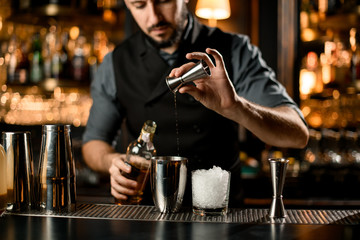 Fototapeta na wymiar Bartender pouring cocktail with shaker and jigger
