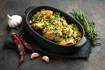 Baked chicken in garlic sauce with cilantro, herbs and spices on a dark background. Chkmeruli is a traditional dish of Caucasian Georgian cuisine.