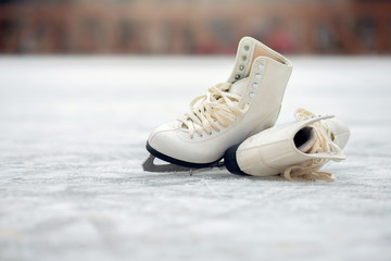 A pair of White Figure Skates lie on an open ice rink