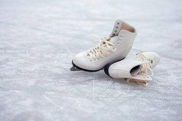 A pair of White Figure Skates lie on an open ice rink